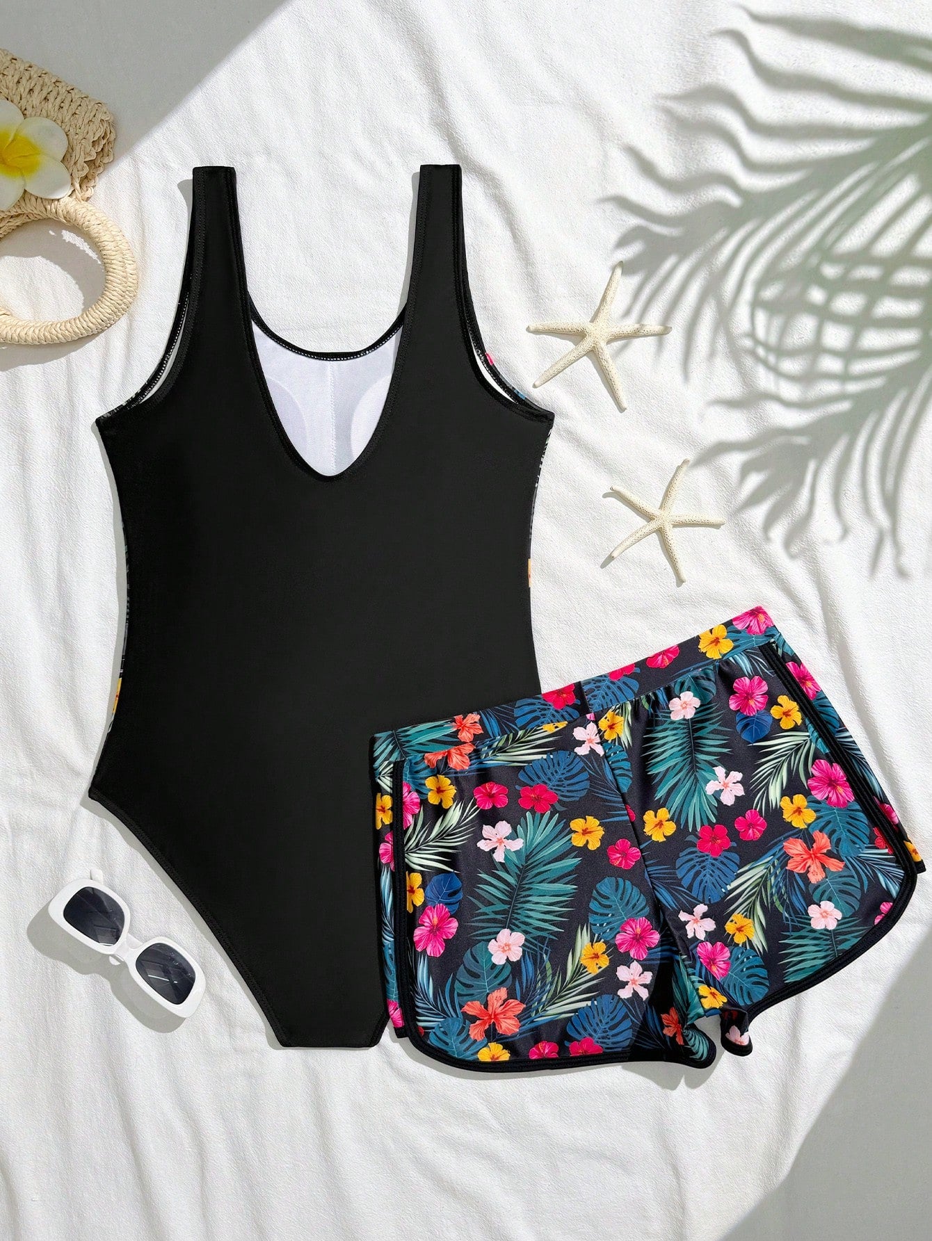 Tween girls 2-piece swimsuit set in black with full floral and plant print, featuring a sleeveless scoop-neck swim top and matching shorts-style bottoms.