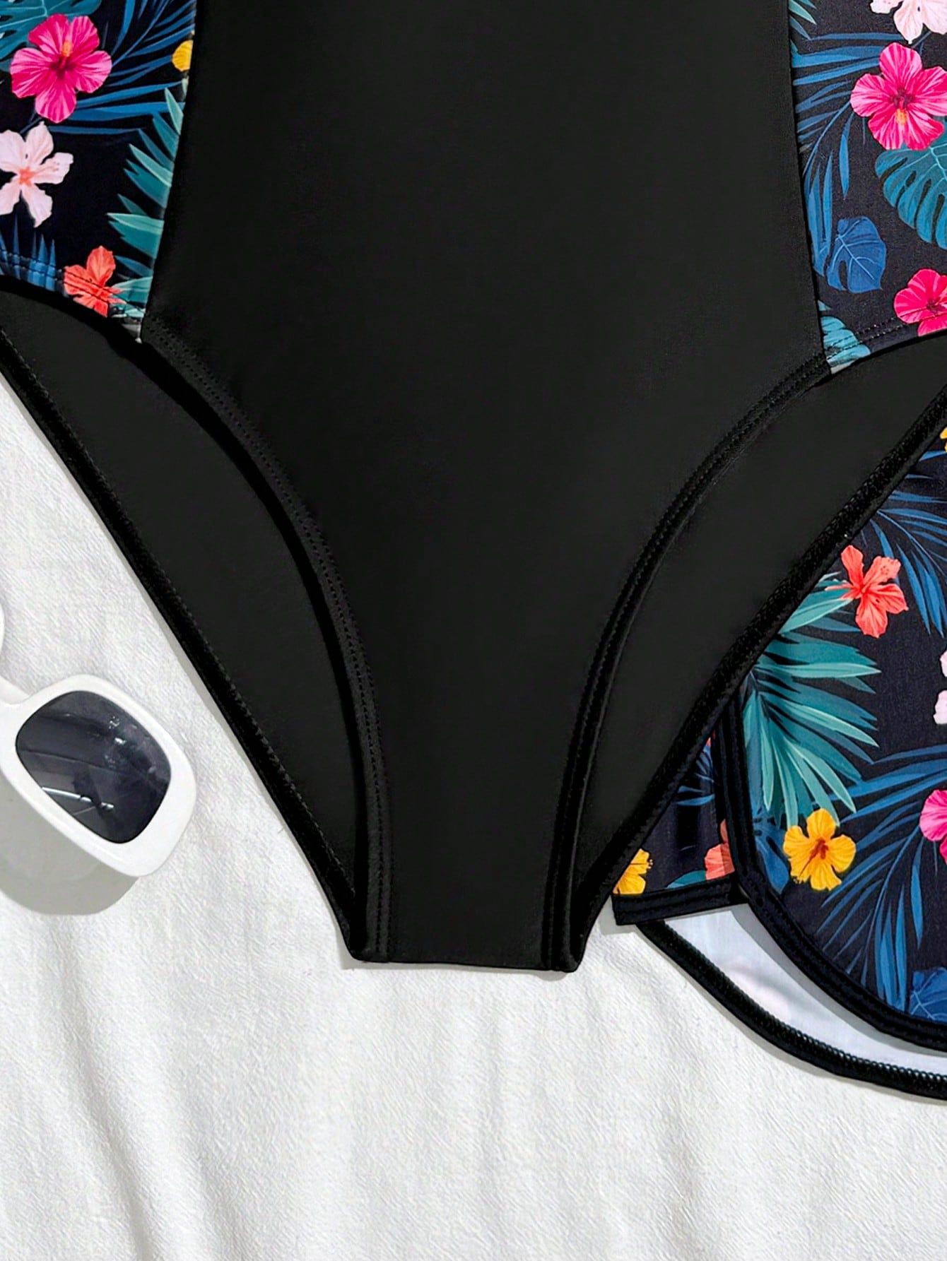Tween girls 2-piece swimsuit set in black with full floral and plant print, featuring a sleeveless scoop-neck swim top and matching shorts-style bottoms.