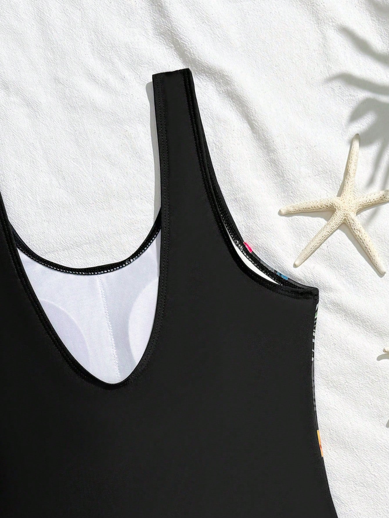 Tween girls 2-piece swimsuit set in black with full floral and plant print, featuring a sleeveless scoop-neck swim top and matching shorts-style bottoms.