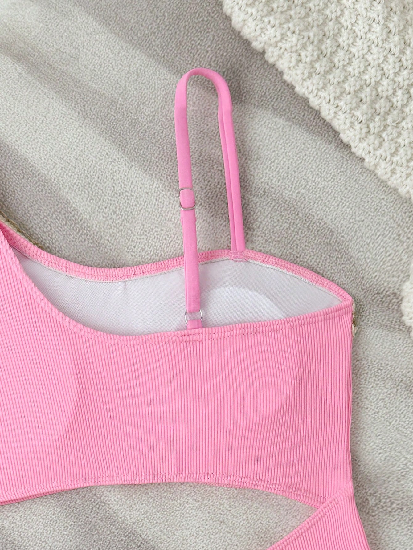 Girls black one-piece swimsuit with asymmetrical neckline, cutout waist detail, colorblock design, and medium-stretch swimsuit fabric for beach and pool wear.