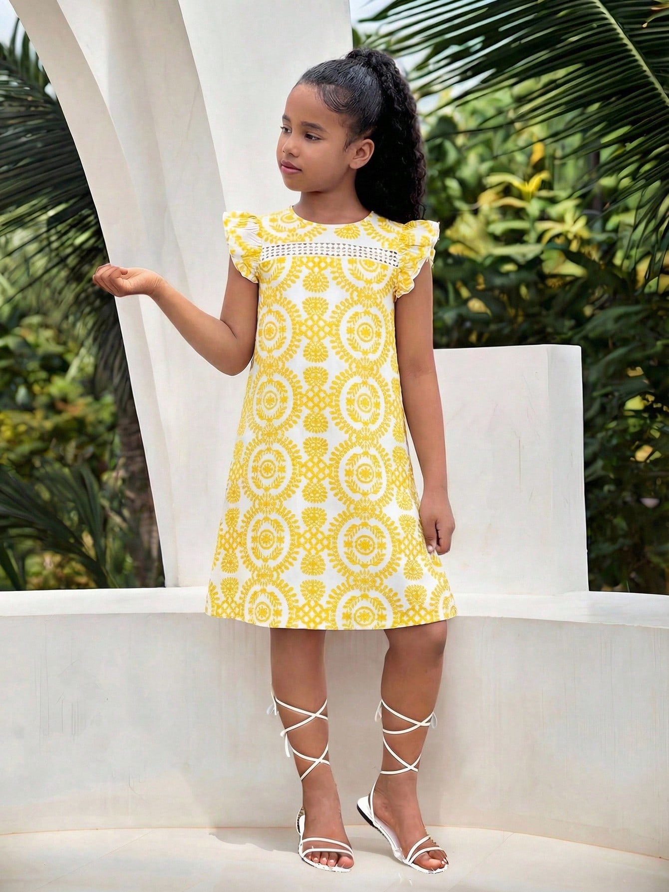 Tween girl wearing a blue ditsy floral patchwork tunic dress with ruffle button details and a round neckline.