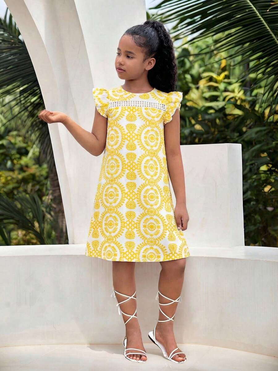 Tween girl wearing a blue ditsy floral patchwork tunic dress with ruffle button details and a round neckline.