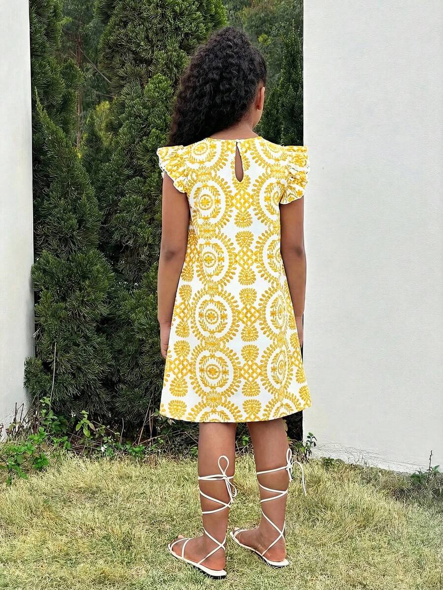 Tween girl wearing a blue ditsy floral patchwork tunic dress with ruffle button details and a round neckline.