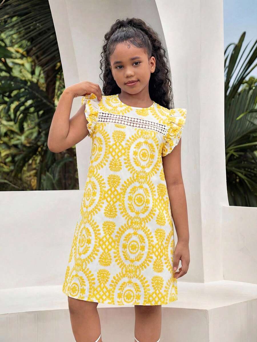 Tween girl wearing a blue ditsy floral patchwork tunic dress with ruffle button details and a round neckline.