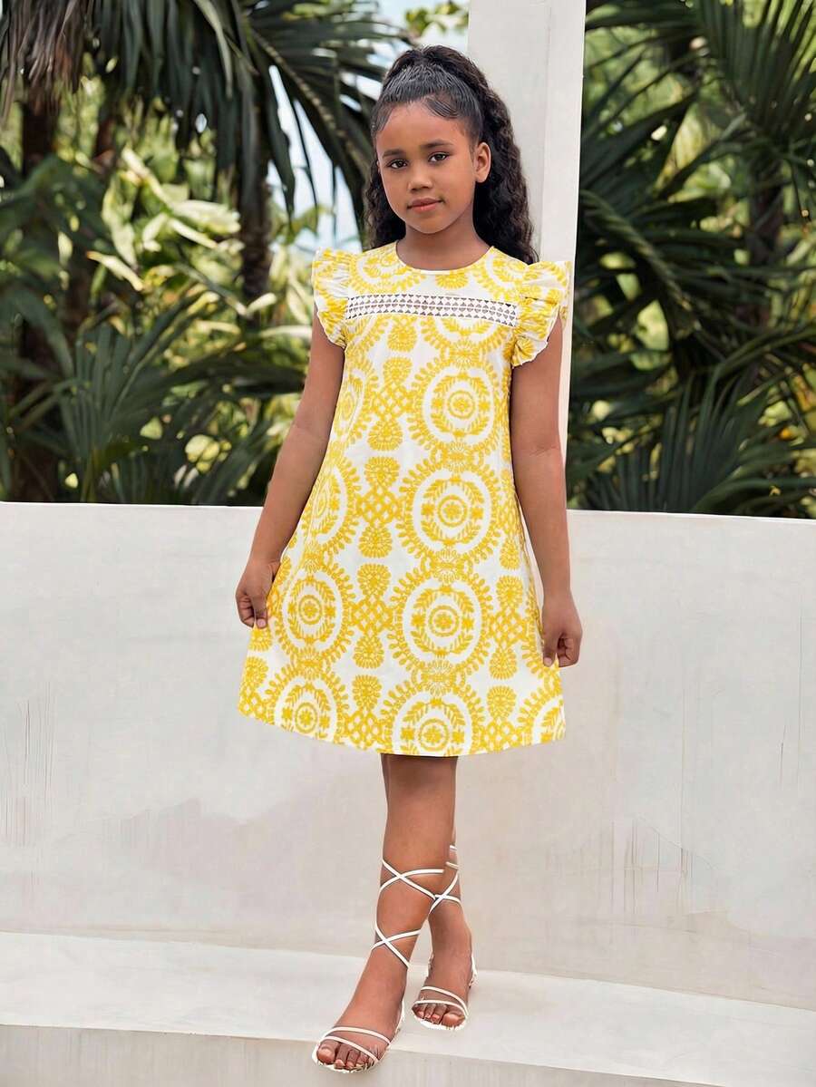 Tween girl wearing a blue ditsy floral patchwork tunic dress with ruffle button details and a round neckline.