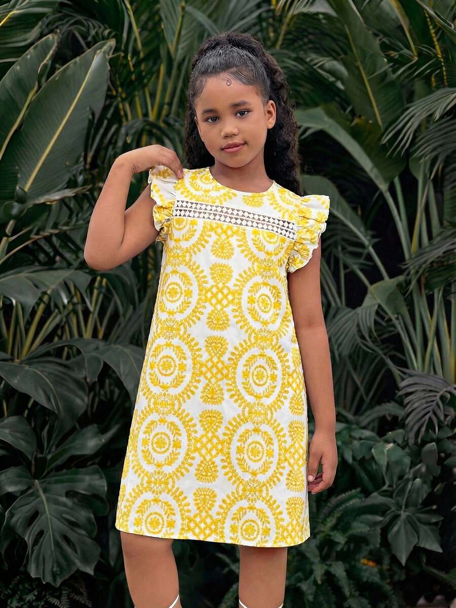 Tween girl wearing a blue ditsy floral patchwork tunic dress with ruffle button details and a round neckline.