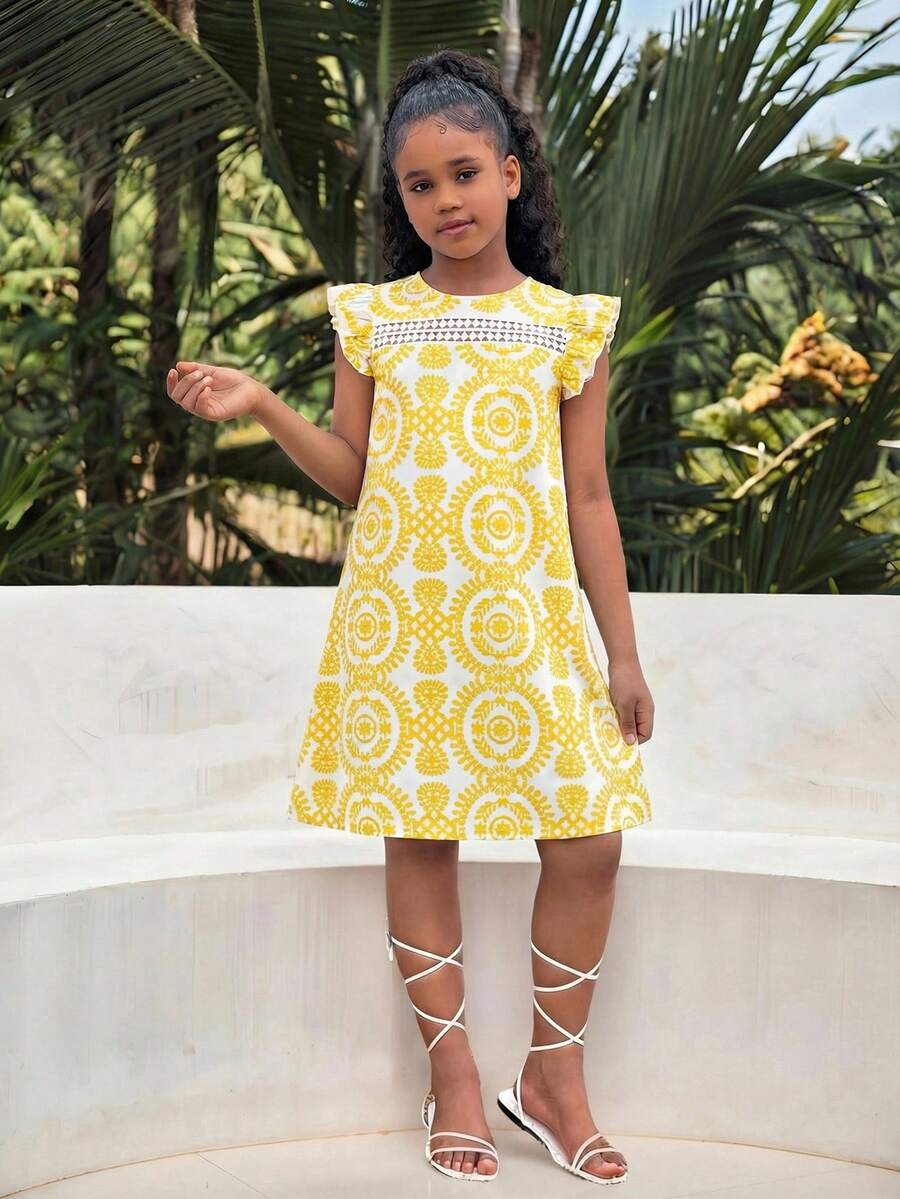 Tween girl wearing a blue ditsy floral patchwork tunic dress with ruffle button details and a round neckline.