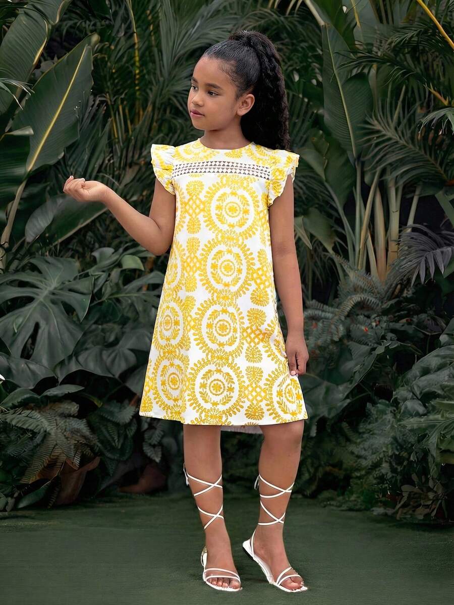 Tween girl wearing a blue ditsy floral patchwork tunic dress with ruffle button details and a round neckline.