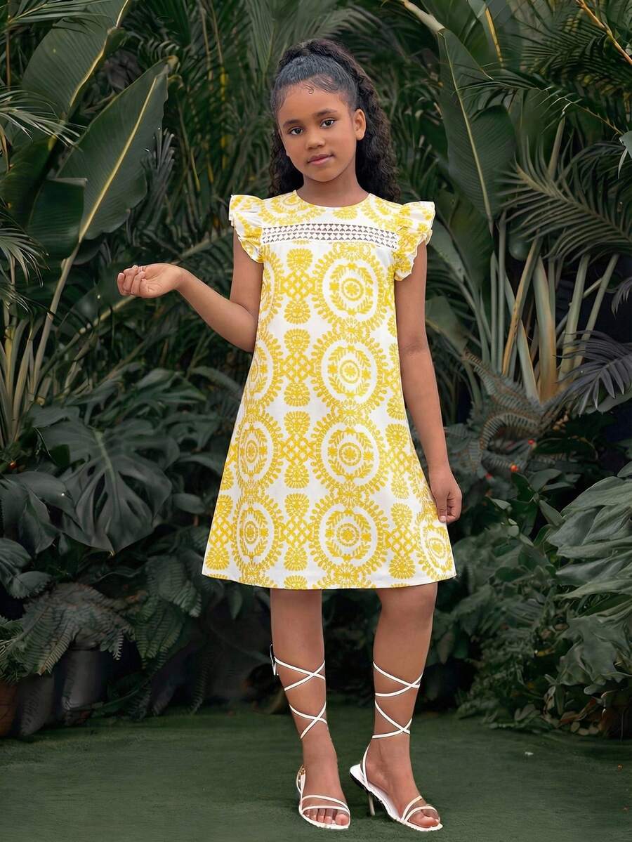 Tween girl wearing a blue ditsy floral patchwork tunic dress with ruffle button details and a round neckline.