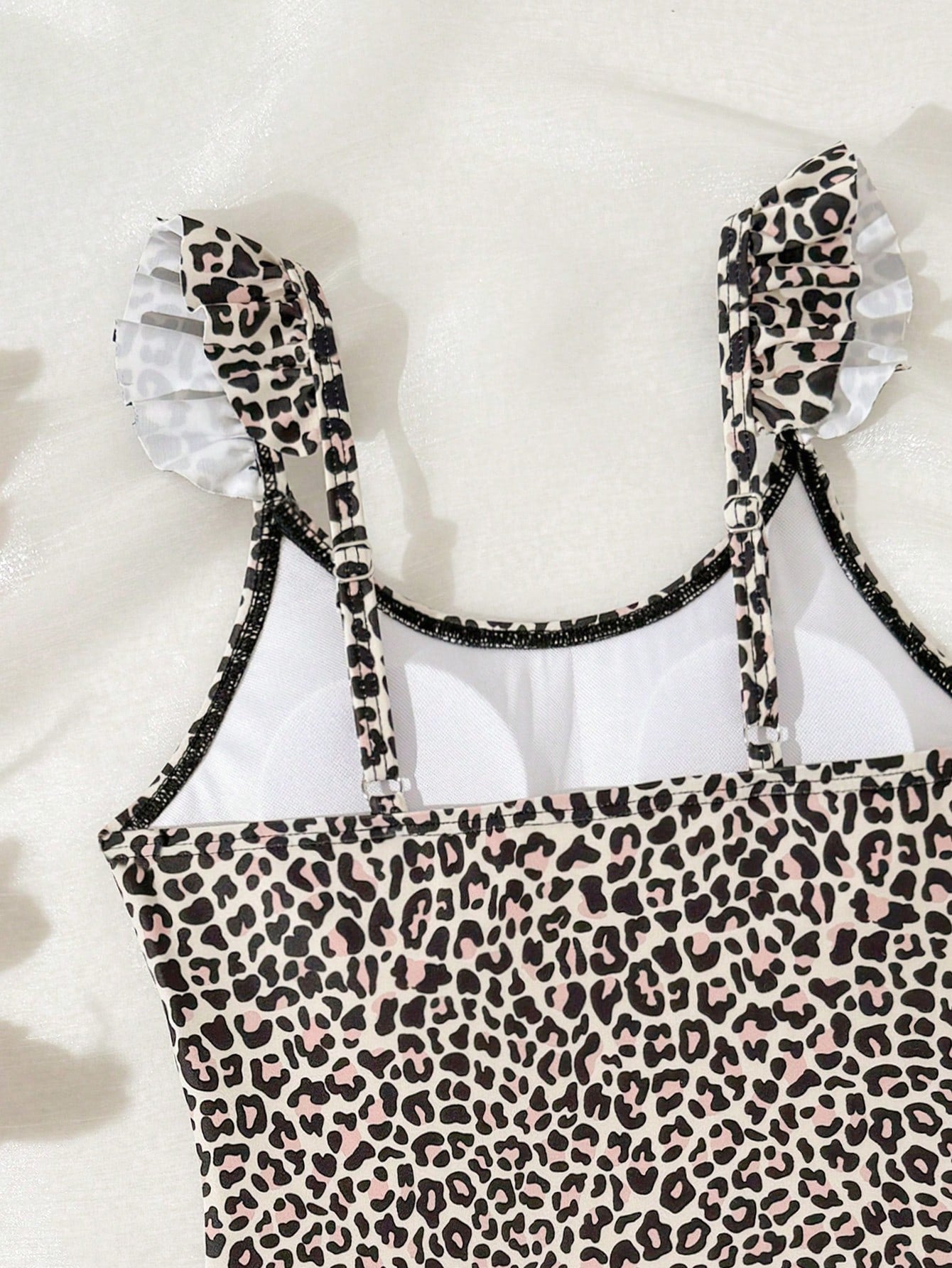 Tween girls one-piece swimsuit in leopard print with ruffle shoulder straps, scoop neckline, fitted shape, and attached ruffle hem skirt; sleeveless, mid-waist skirt bottom, and lined body for swimming, vacation, and summer beach wear.