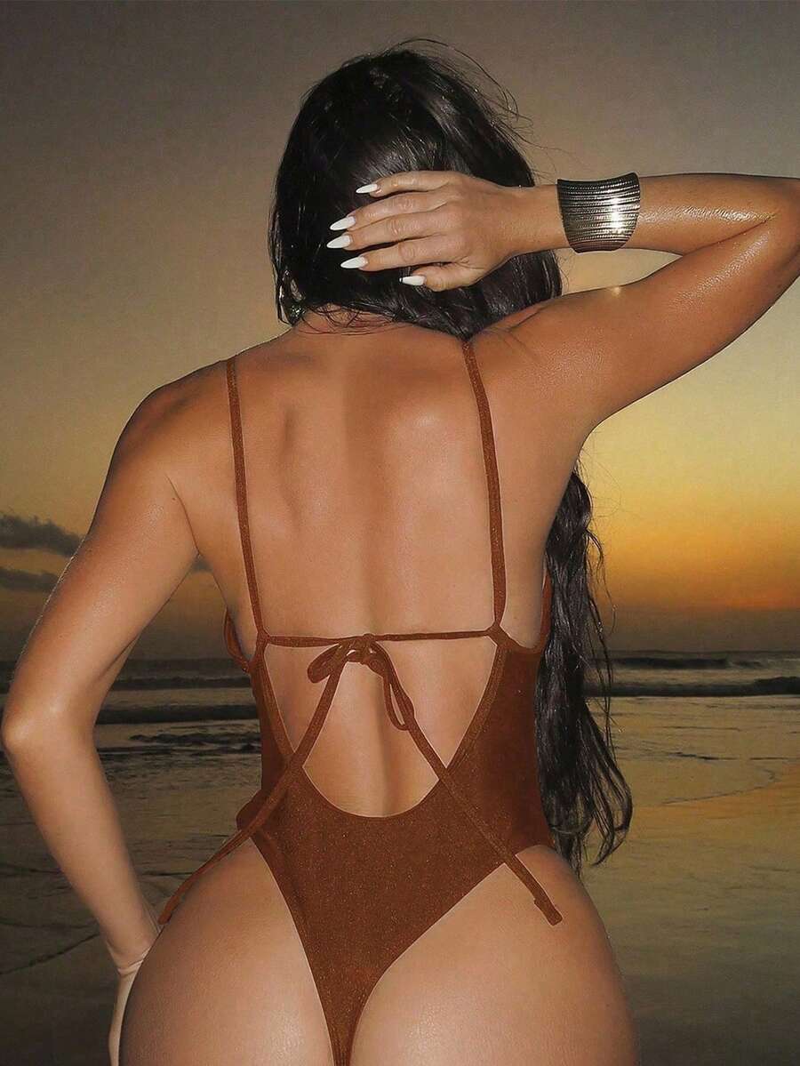 Women's black lace one-piece swimsuit featuring a deep V-neckline, spaghetti straps, backless tie-up detail, and thong bottom.