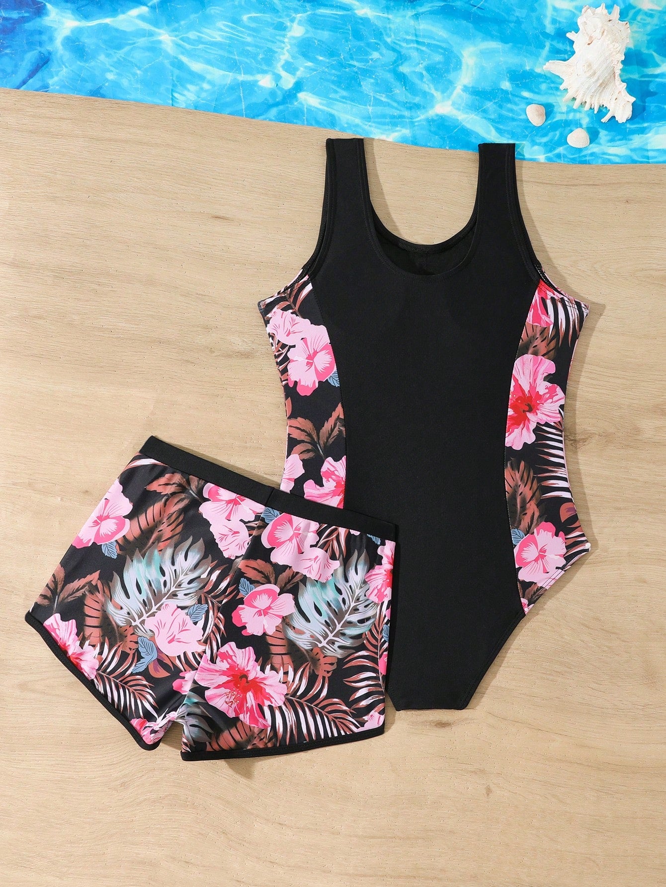 Tween girls 2-piece swimsuit set in black with full floral and plant print, featuring a sleeveless scoop-neck swim top and matching shorts-style bottoms.
