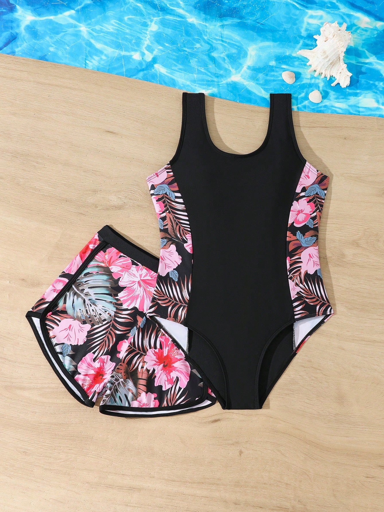 Tween girls 2-piece swimsuit set in black with full floral and plant print, featuring a sleeveless scoop-neck swim top and matching shorts-style bottoms.