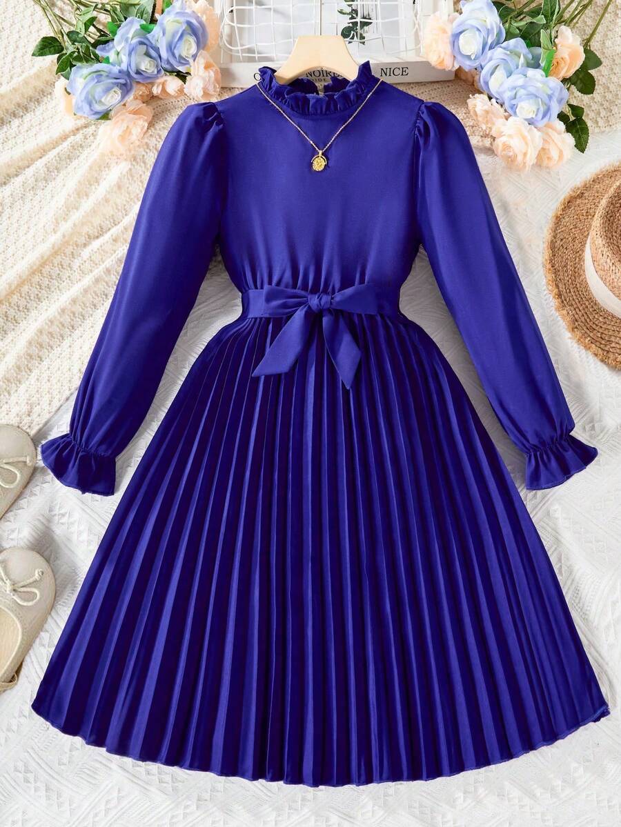 Tween girl wearing a royal blue long sleeve pleated casual A-line dress featuring a stand collar, flare sleeves, high waist with front tie belt, and ruffle hem.