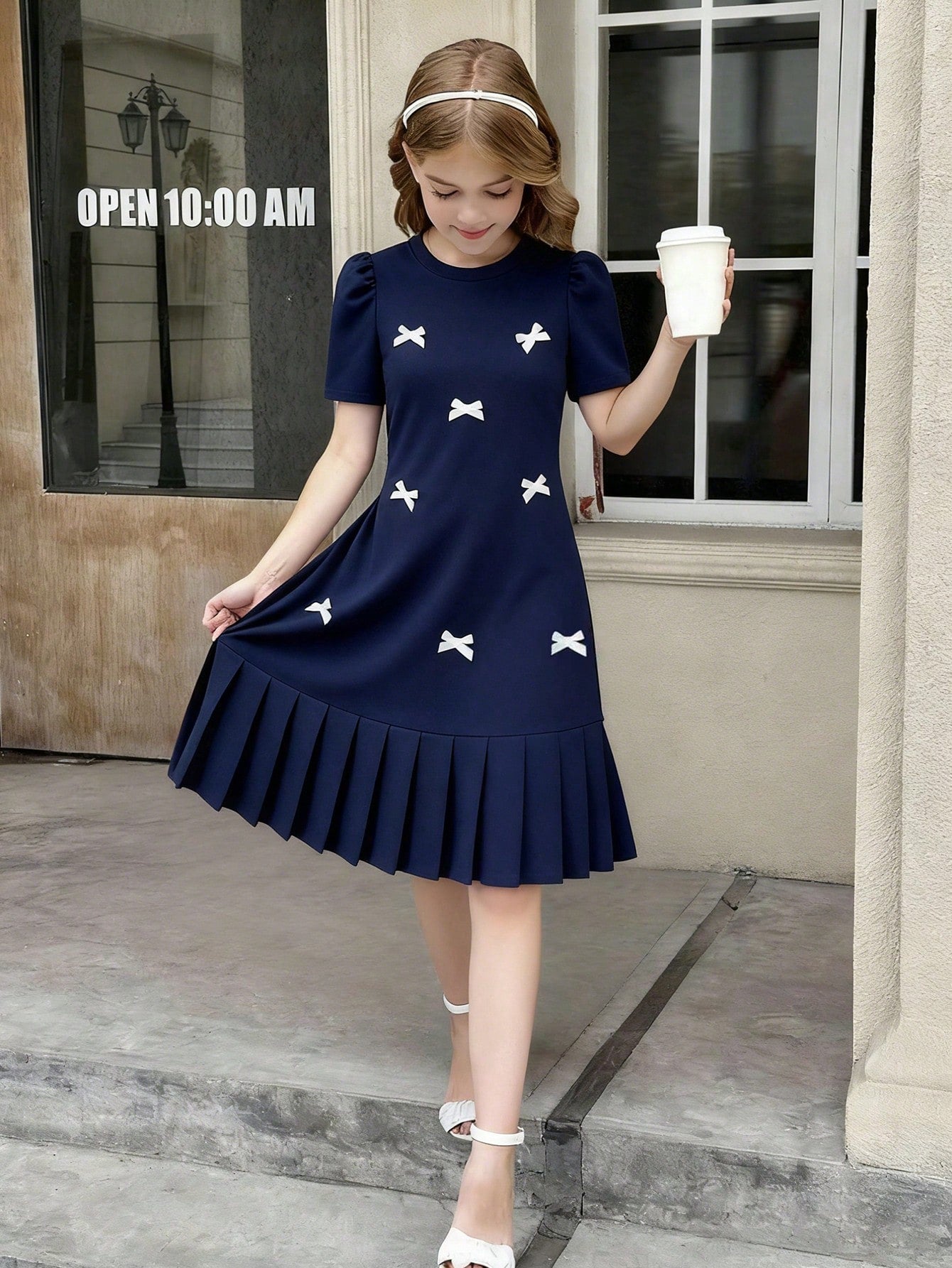 Tween girls apricot short-sleeve pleated smock dress with 3D bow decor and round neckline.