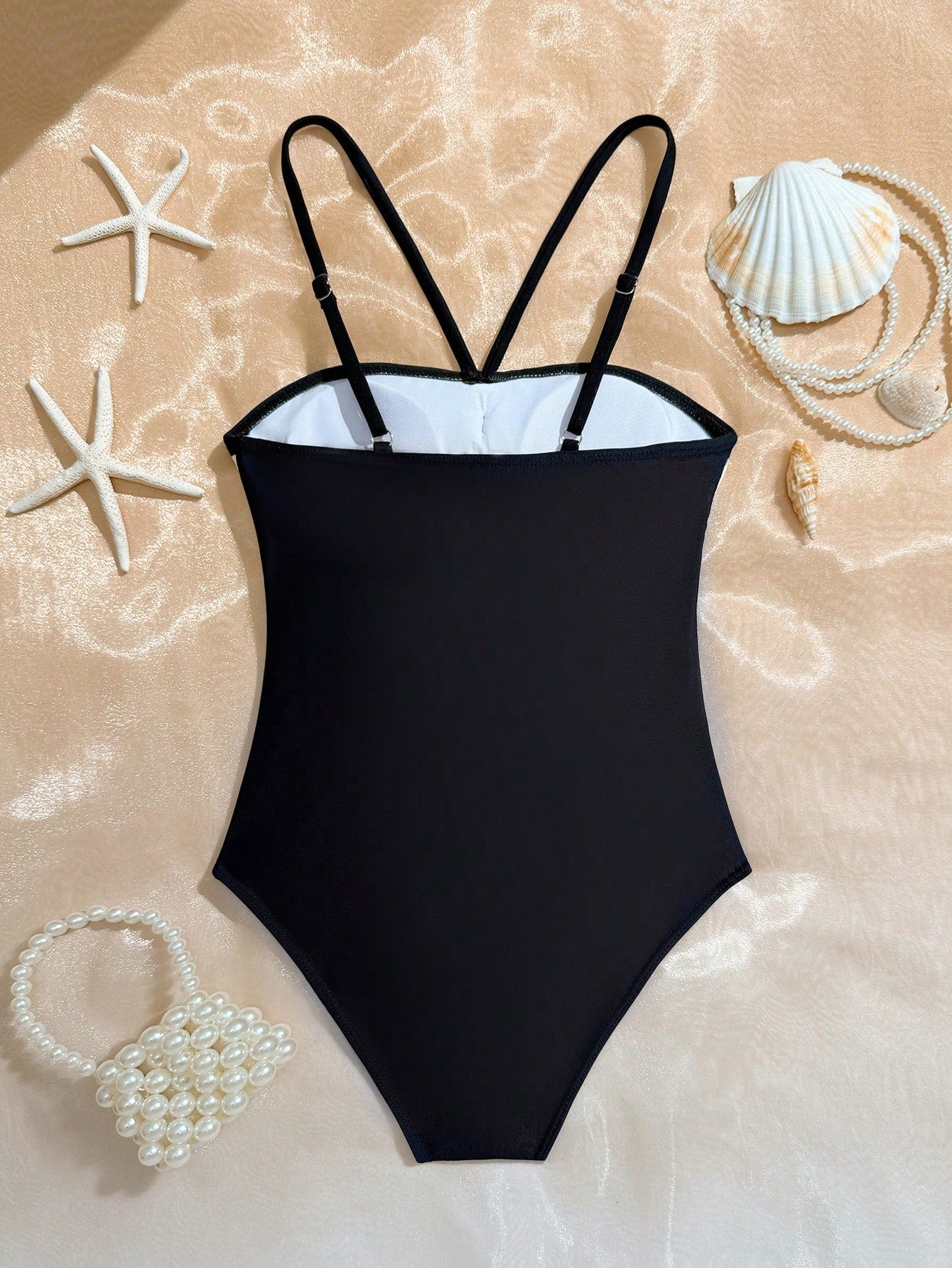 Tween girls one-piece swimsuit with a floral plant print, spaghetti straps, and a mid-waist fit in black.