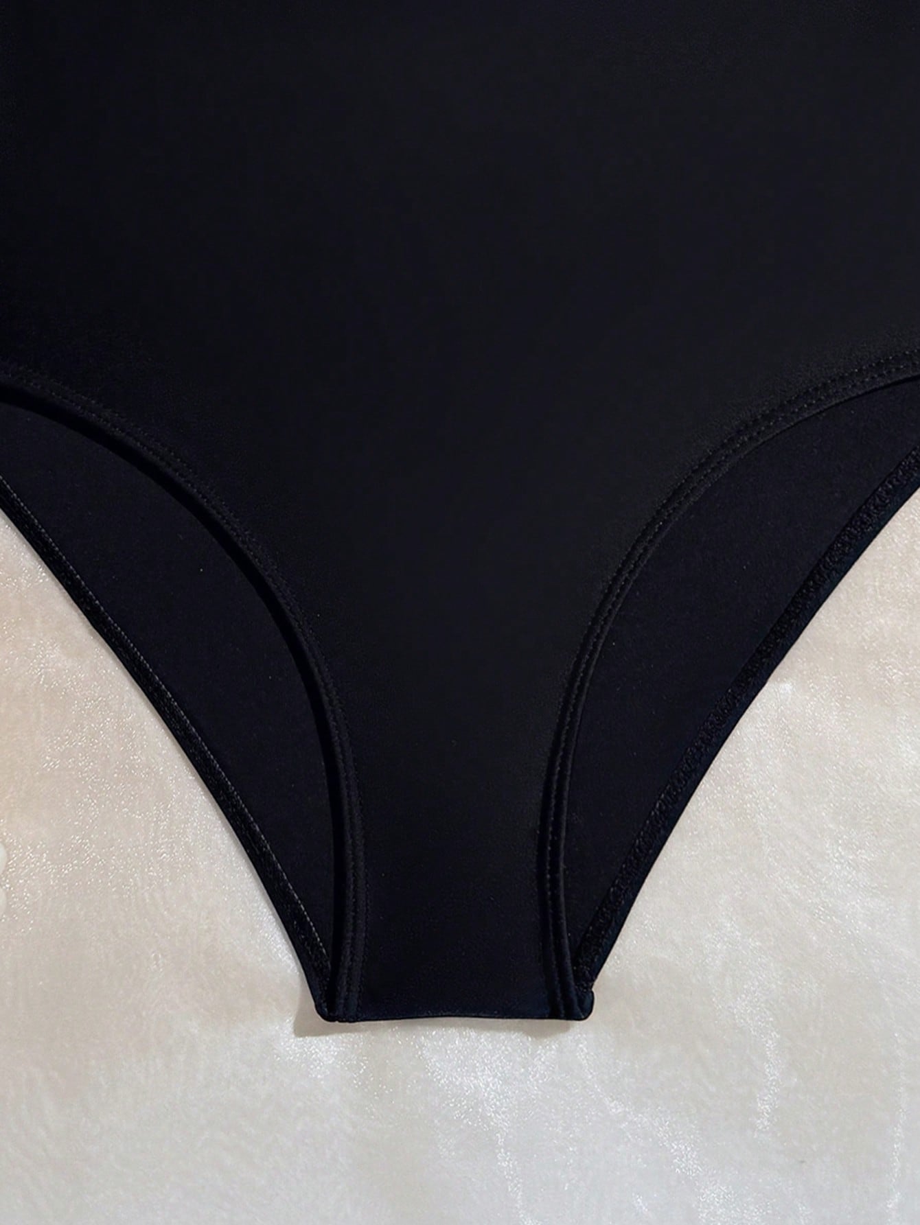 Tween girls one-piece swimsuit with a floral plant print, spaghetti straps, and a mid-waist fit in black.