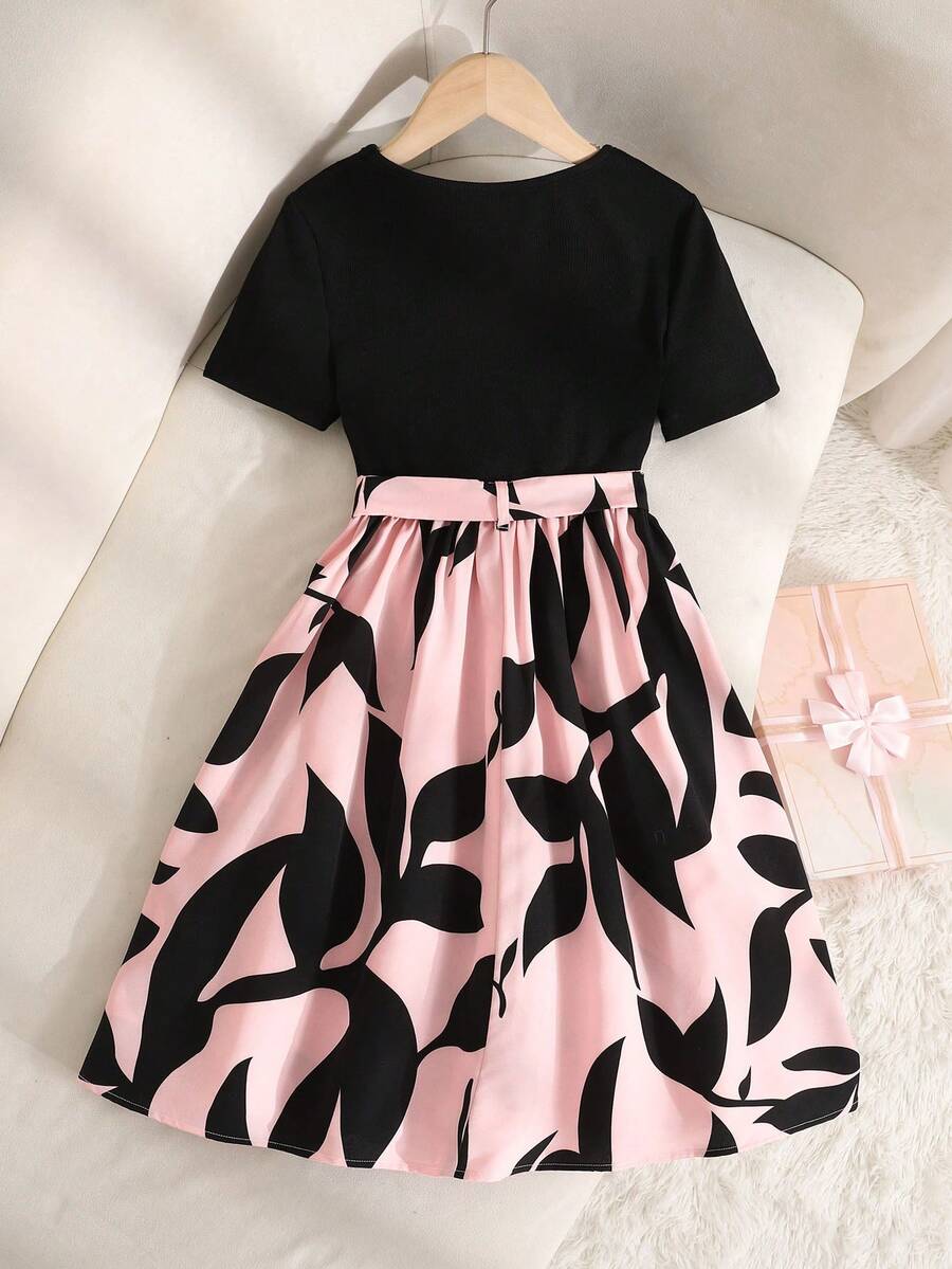 Tween girl wearing an apricot short sleeve A-line dress featuring a round neck, high waist with a belt, and flared hem.