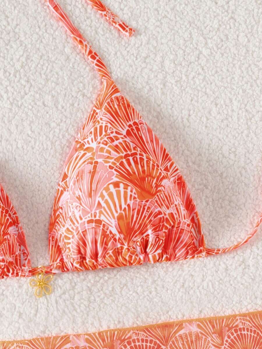 Women's 3-piece blue tropical shell print bikini set featuring a halter bralette top, low-waist tie-side bottom, and a matching sheer mesh cover-up skirt.