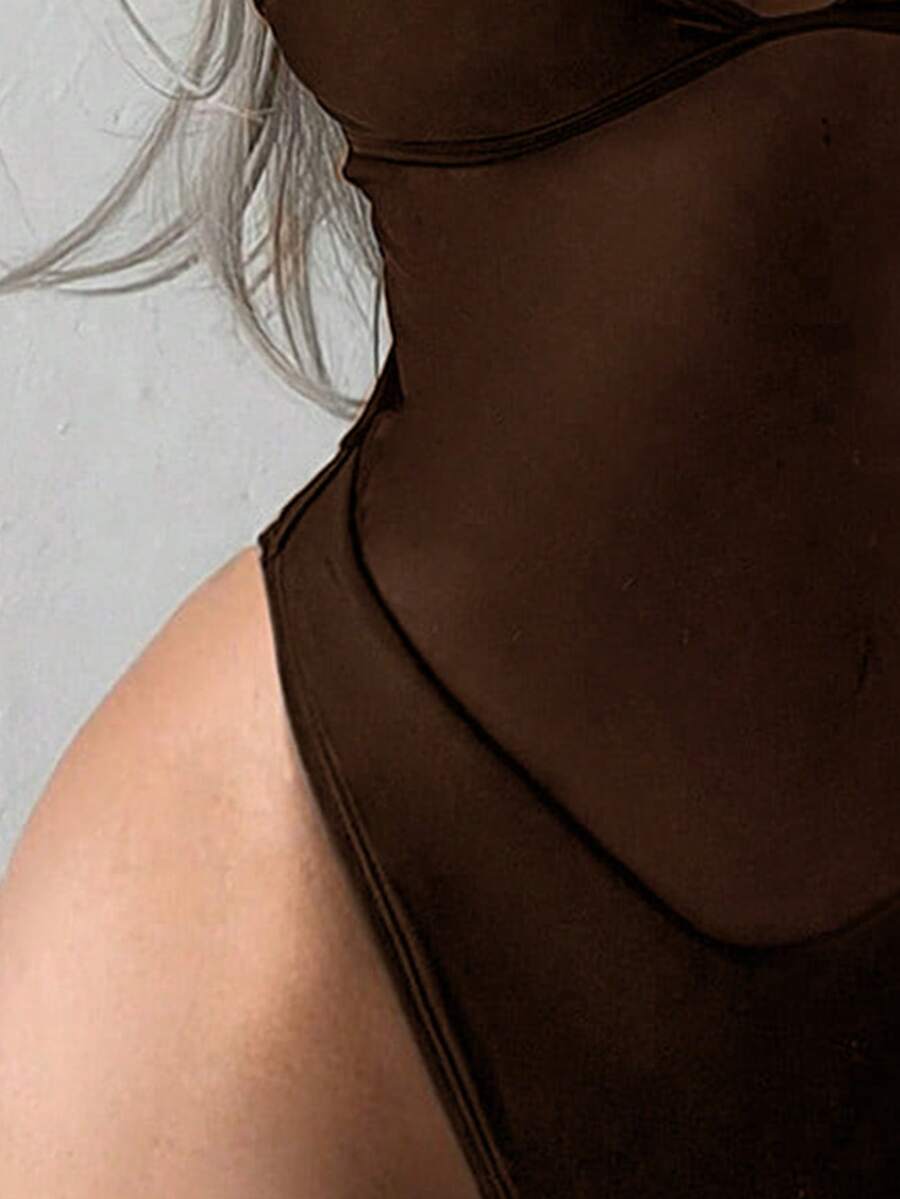 Women's black one-piece swimsuit with mesh patchwork detailing, spaghetti straps, backless style, and high cut bottom.