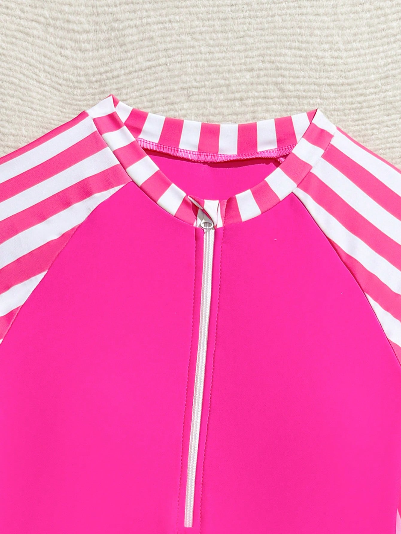 Tween girls one-piece rash guard swimsuit with long sleeves, high neck, front zipper, and ocean shell graphic print in a fitted style for beach, swimming, and vacation wear.