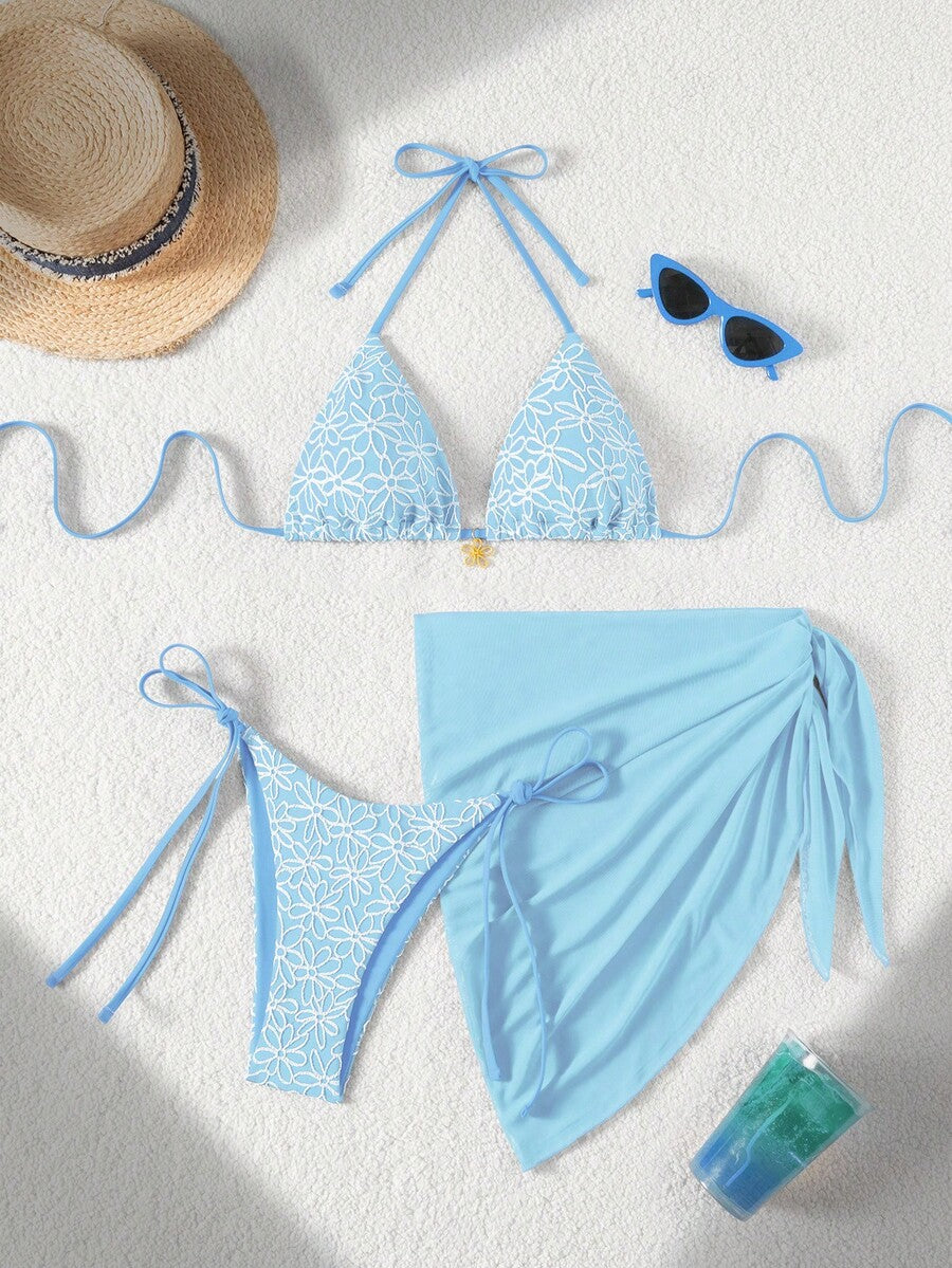 Women's 3-piece blue tropical shell print bikini set featuring a halter bralette top, low-waist tie-side bottom, and a matching sheer mesh cover-up skirt.