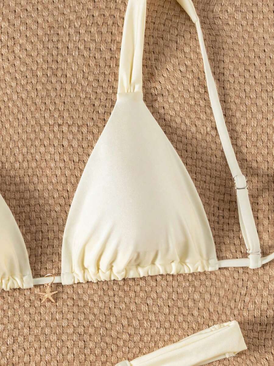 Women's 2-piece triangle cup bikini set in solid color featuring woven pearl shell decoration, halter neckline, and high-waist side-tie ruched bottoms.