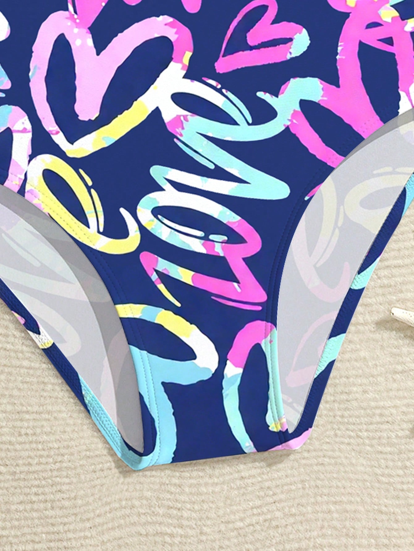 Tween girls one-piece swimsuit with a black base and multicolor tropical plant print featuring bamboo, palm leaves, plumeria flowers, scoop neck, and wide straps.