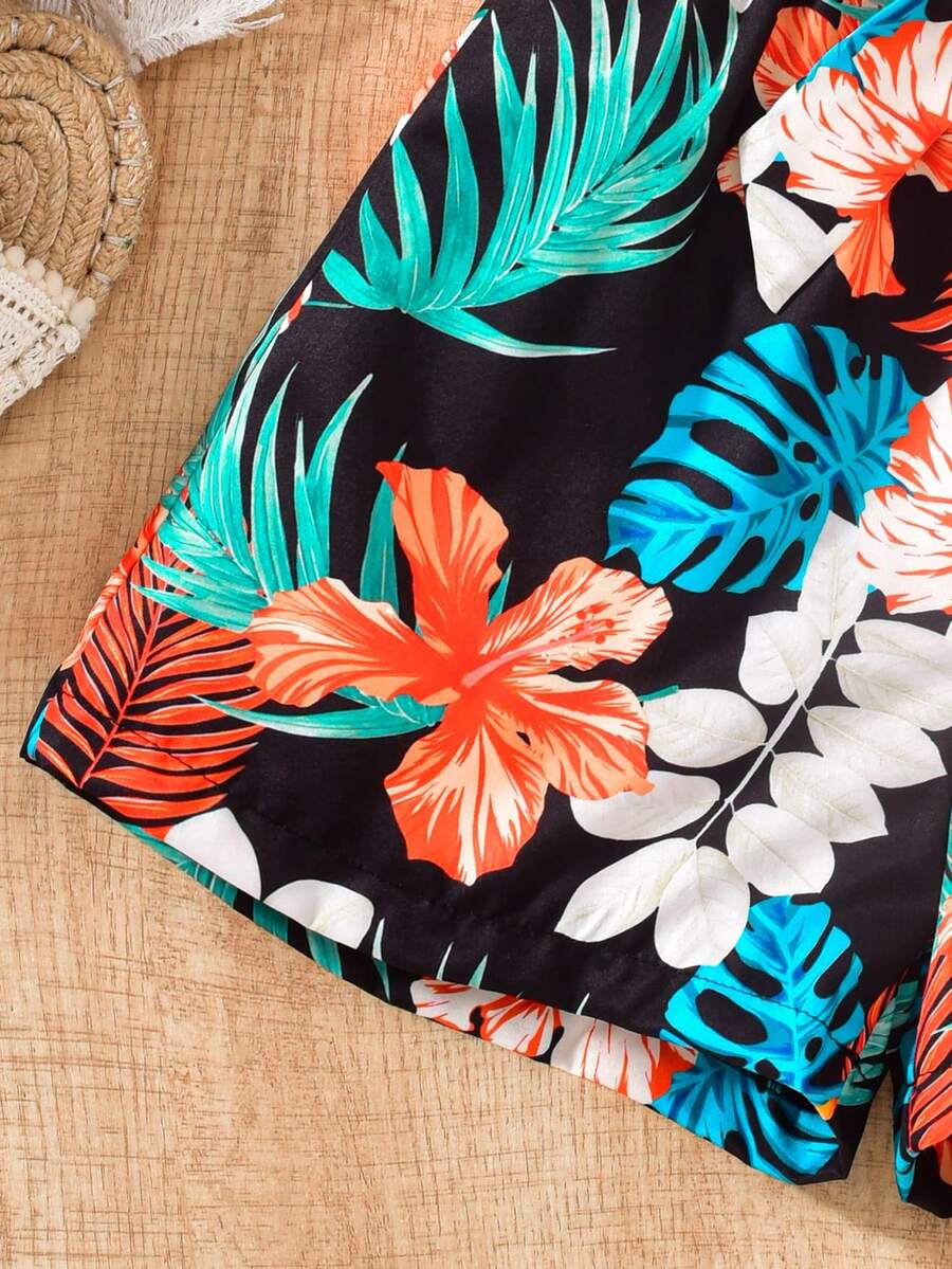 Tween girls 2-piece summer set featuring a black off-shoulder crop top with spaghetti straps and tropical leaf print ruffled paperbag waist shorts with a matching belt.