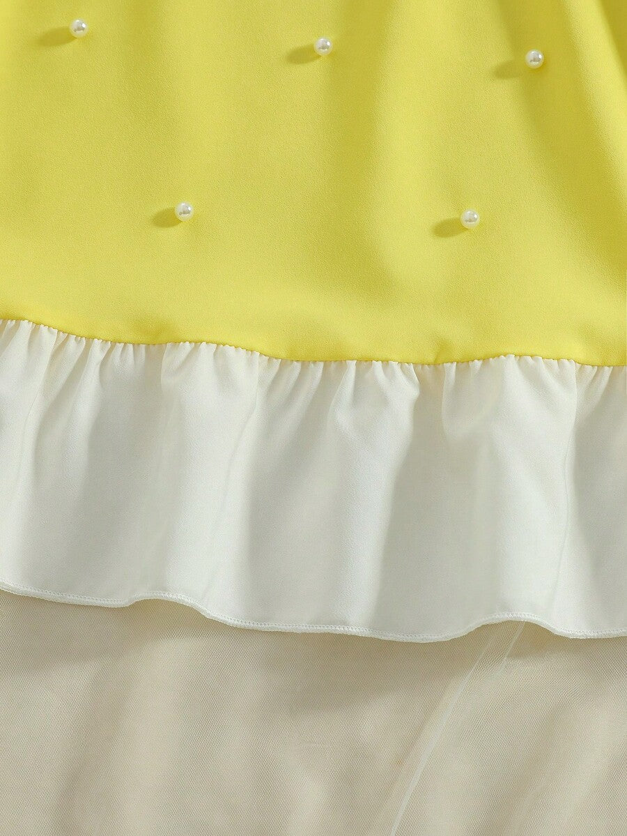 Yellow sleeveless colorblock dress for girls featuring a round neck, ruffle hem, and front bow detail.