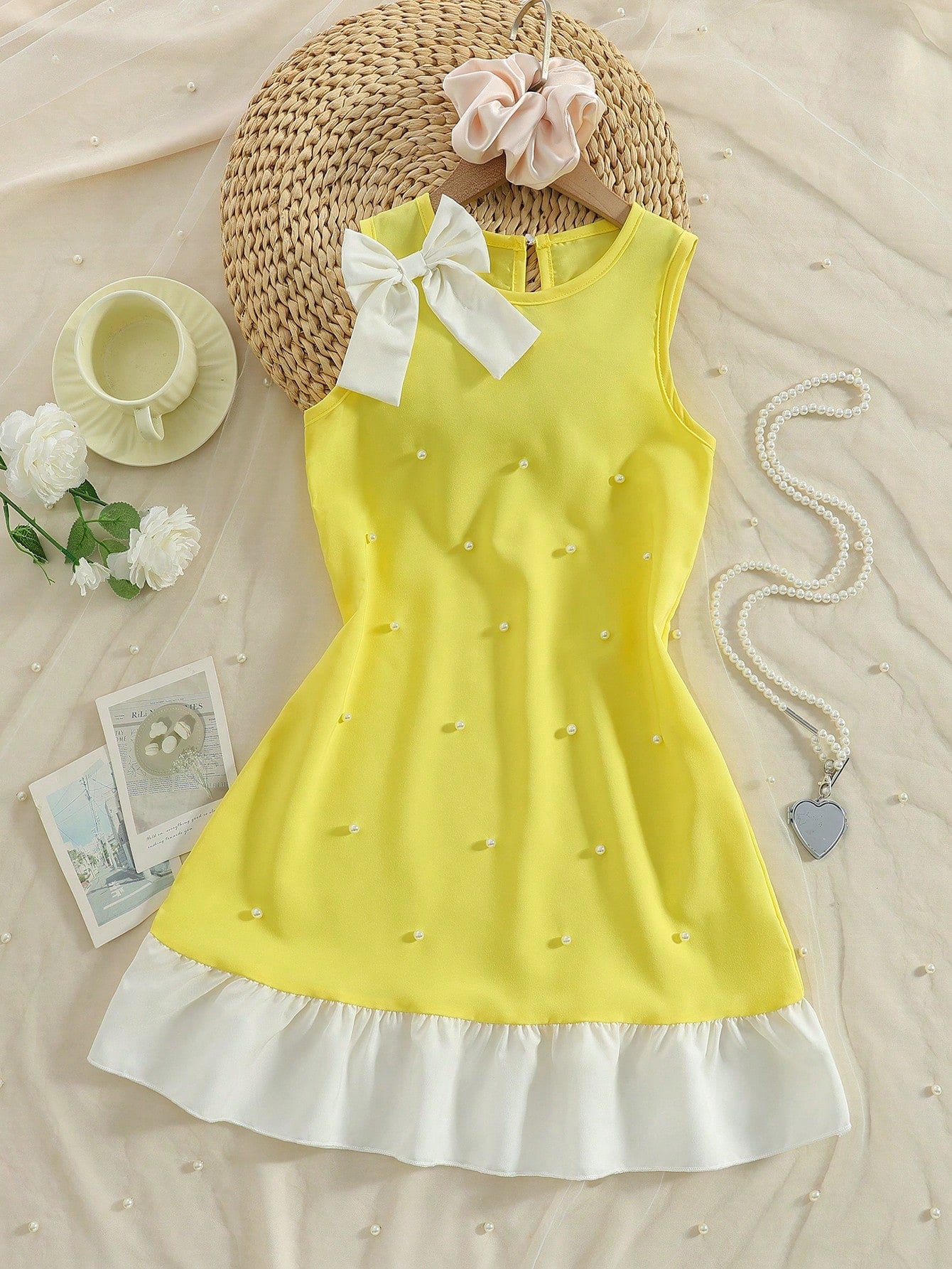 Yellow sleeveless colorblock dress for girls featuring a round neck, ruffle hem, and front bow detail.