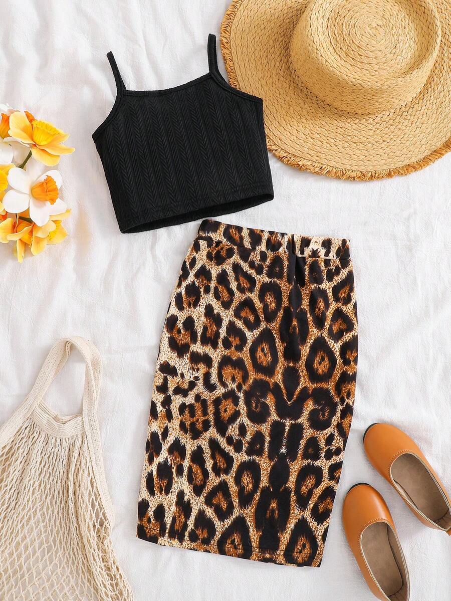 Tween girl wearing a 2-piece set featuring a black rib-knit spaghetti strap camisole top and a ruched leopard print midi skirt.