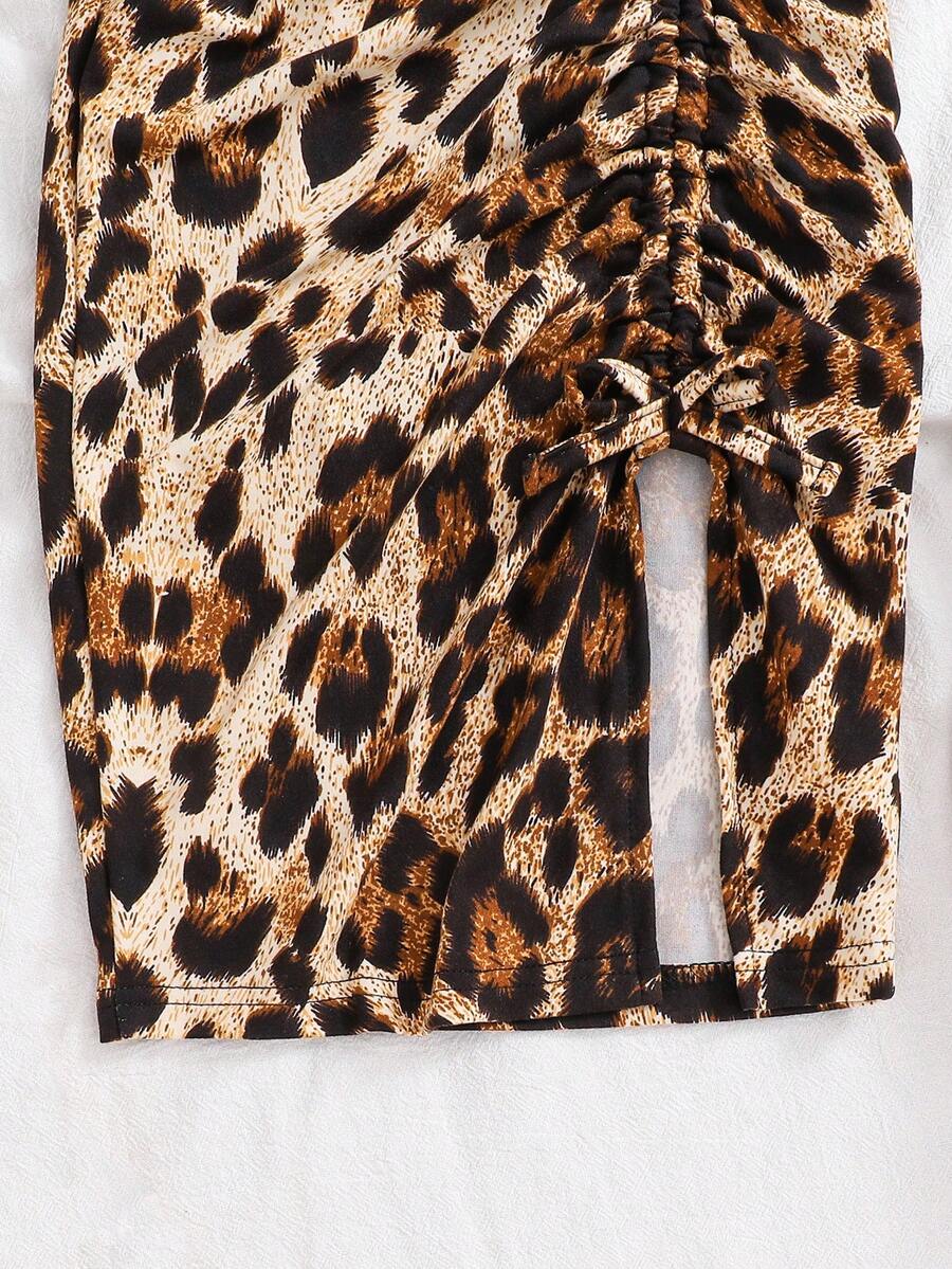 Tween girl wearing a 2-piece set featuring a black rib-knit spaghetti strap camisole top and a ruched leopard print midi skirt.