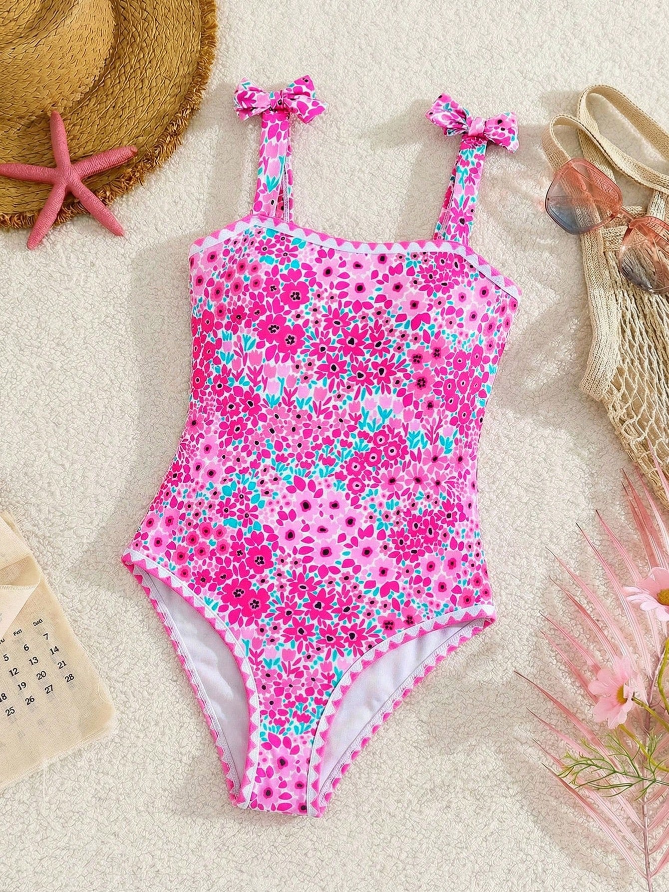 Tween girl floral print one-piece swimsuit with twist front, spaghetti straps, fitted shape, and multicolor all-over hibiscus-inspired pattern for beach and pool wear.