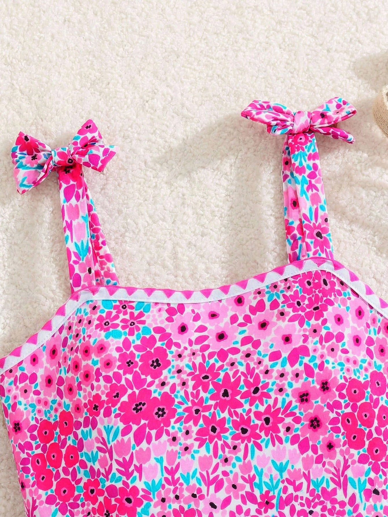 Tween girl floral print one-piece swimsuit with twist front, spaghetti straps, fitted shape, and multicolor all-over hibiscus-inspired pattern for beach and pool wear.