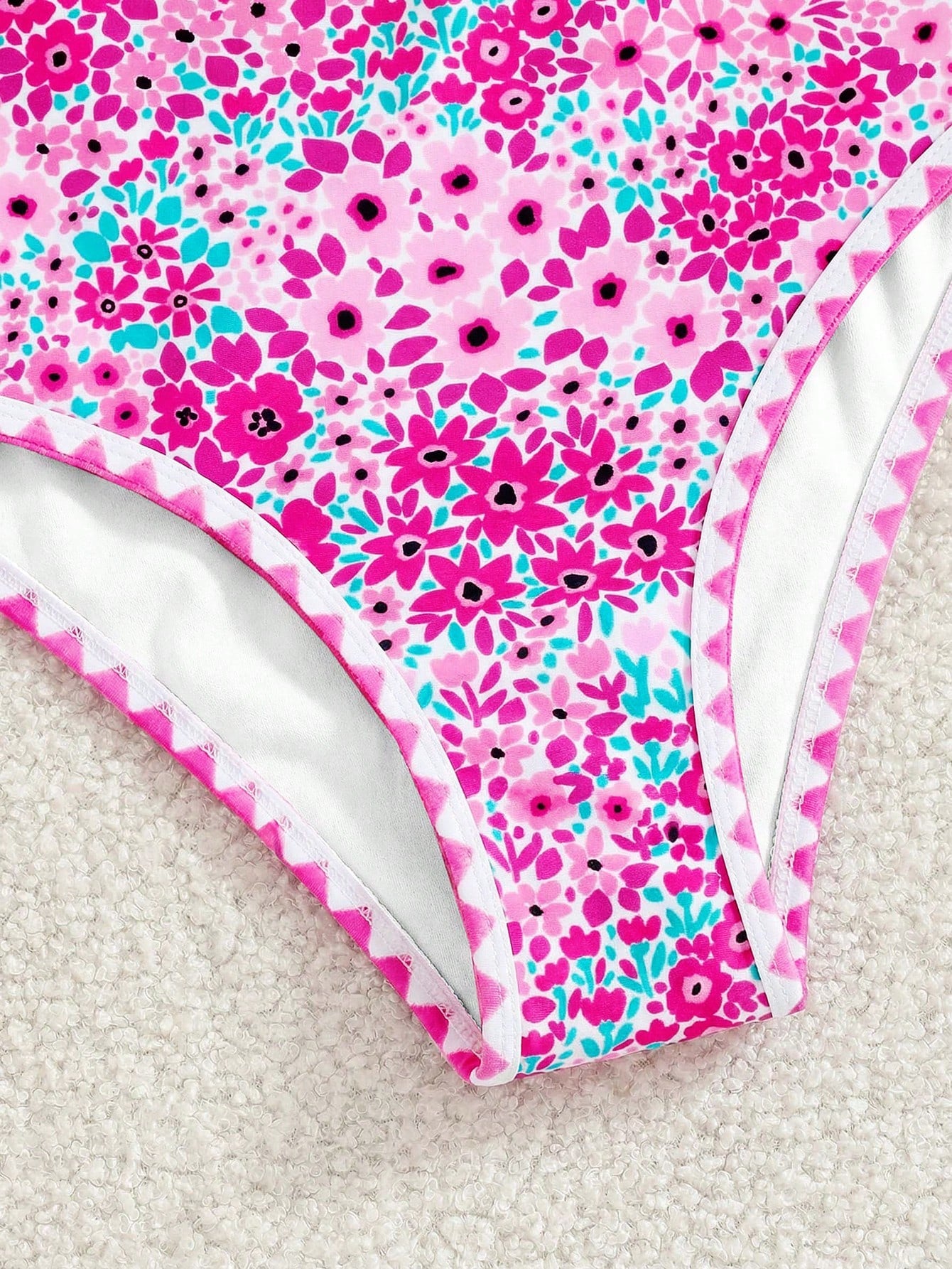 Tween girl floral print one-piece swimsuit with twist front, spaghetti straps, fitted shape, and multicolor all-over hibiscus-inspired pattern for beach and pool wear.