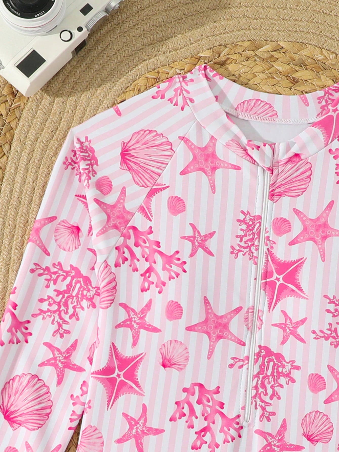 Tween girls one-piece rash guard swimsuit with long sleeves, high neck, front zipper, and ocean shell graphic print in a fitted style for beach, swimming, and vacation wear.