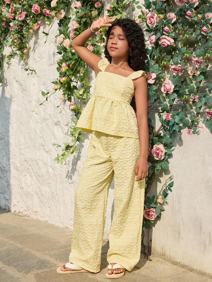 Tween girl wearing an apricot 2-piece outfit set featuring a shirred spaghetti strap short cami top and matching wide-leg long pants.