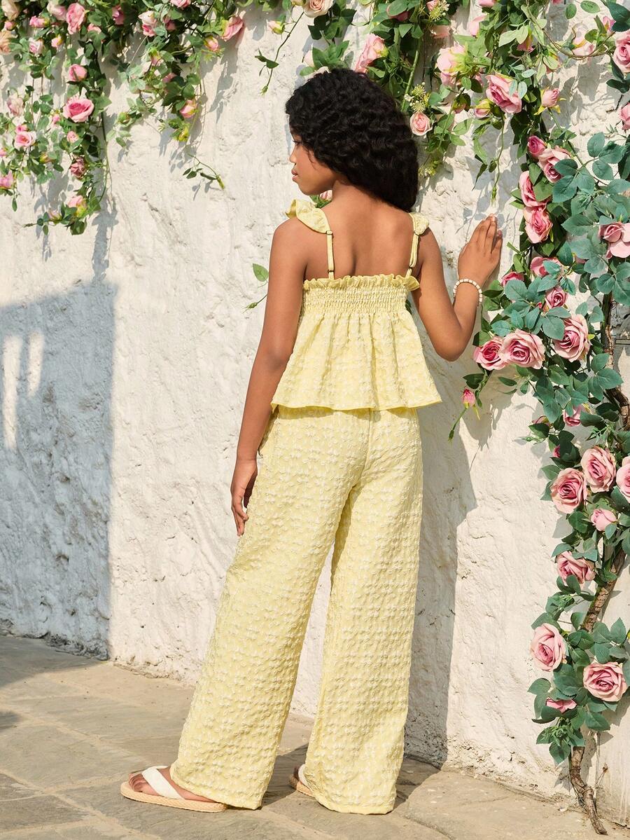 Tween girl wearing an apricot 2-piece outfit set featuring a shirred spaghetti strap short cami top and matching wide-leg long pants.