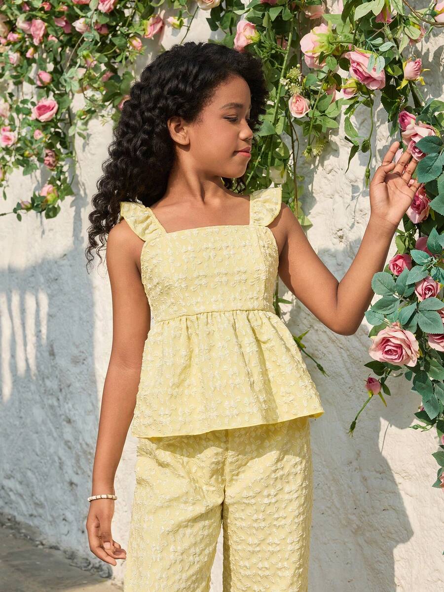 Tween girl wearing an apricot 2-piece outfit set featuring a shirred spaghetti strap short cami top and matching wide-leg long pants.