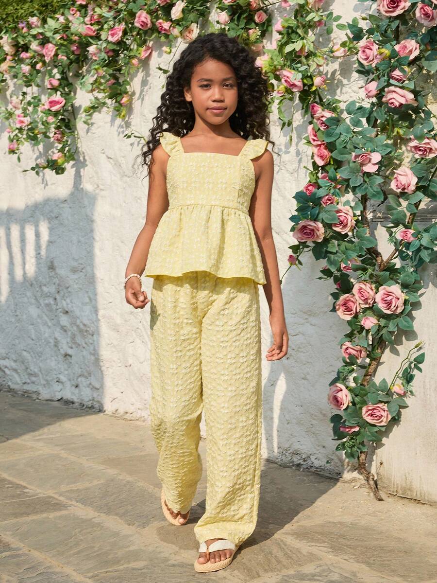 Tween girl wearing an apricot 2-piece outfit set featuring a shirred spaghetti strap short cami top and matching wide-leg long pants.
