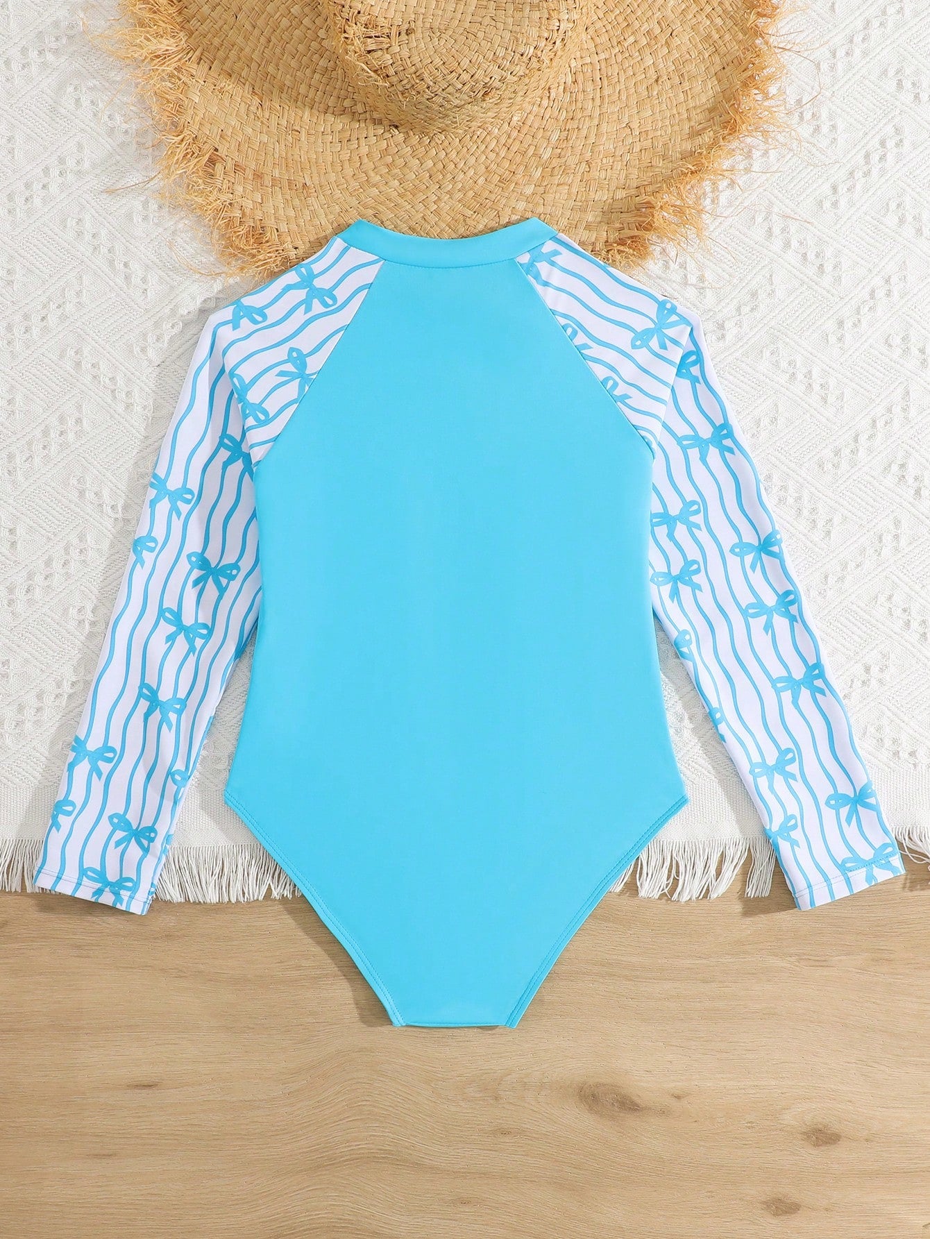 Tween girls one-piece rash guard swimsuit with long sleeves, high neck, front zipper, and ocean shell graphic print in a fitted style for beach, swimming, and vacation wear.