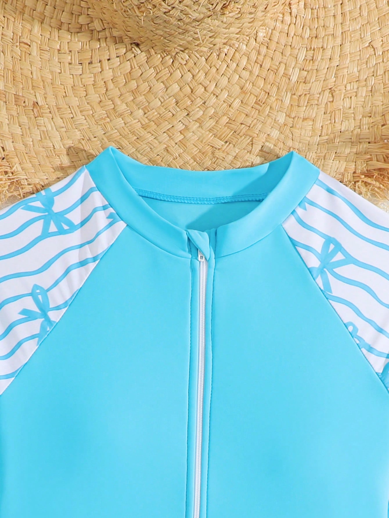Tween girls one-piece rash guard swimsuit with long sleeves, high neck, front zipper, and ocean shell graphic print in a fitted style for beach, swimming, and vacation wear.