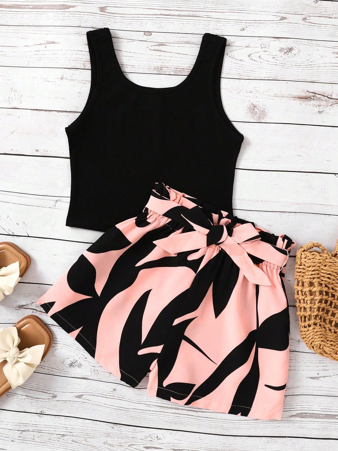 Tween girl wearing a casual 2-piece set featuring a black rib-knit scoop neck tank top and leopard print paperbag waist shorts with a matching belt.