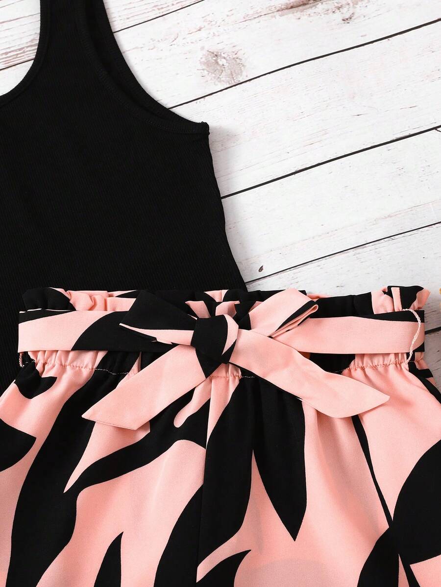 Tween girl wearing a casual 2-piece set featuring a black rib-knit scoop neck tank top and leopard print paperbag waist shorts with a matching belt.