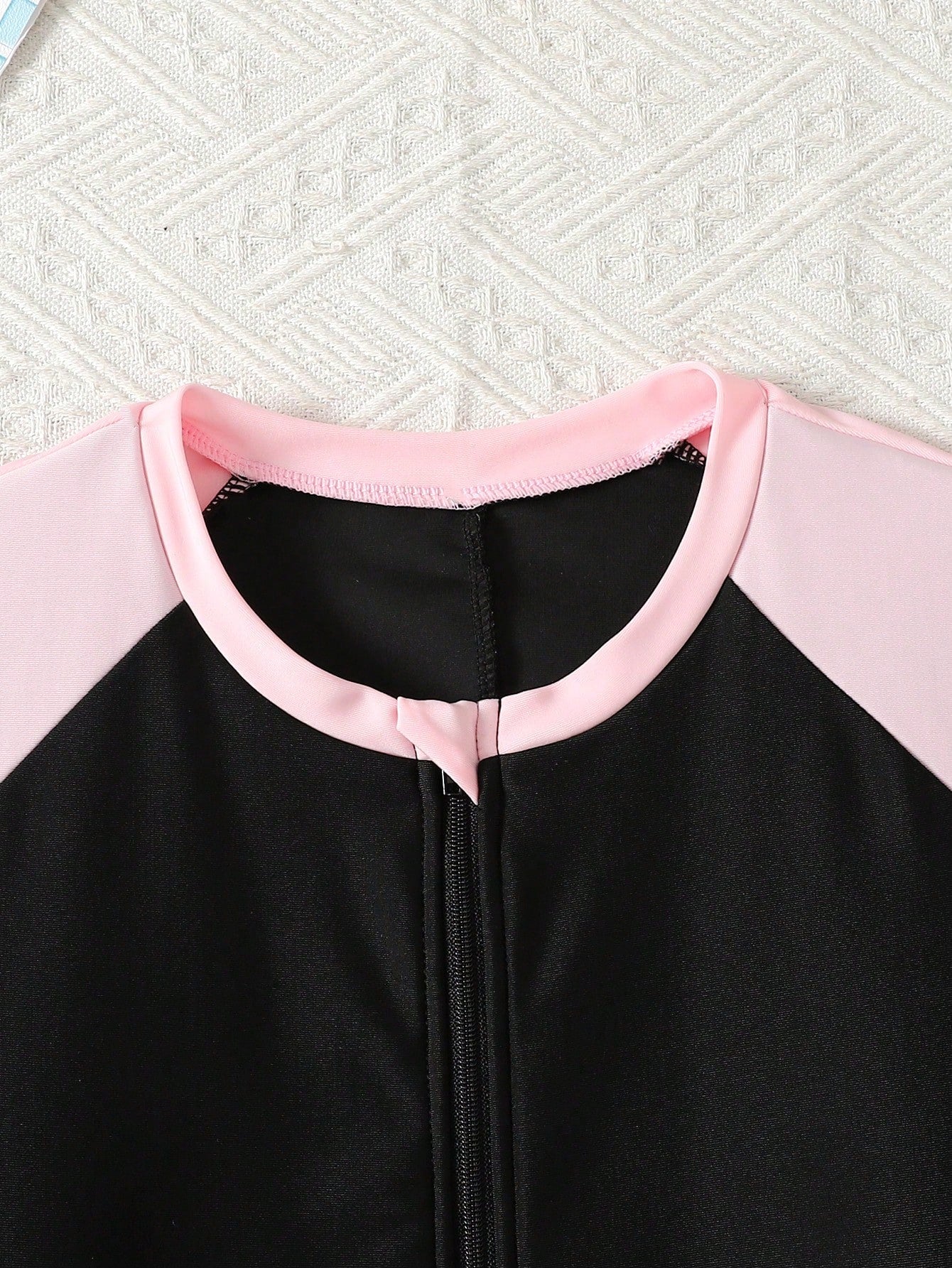 Black and white one-piece rashguard swimsuit for tween girls with short sleeves, high neck, zipper detail, fitted shape, and shorts-style bottom.