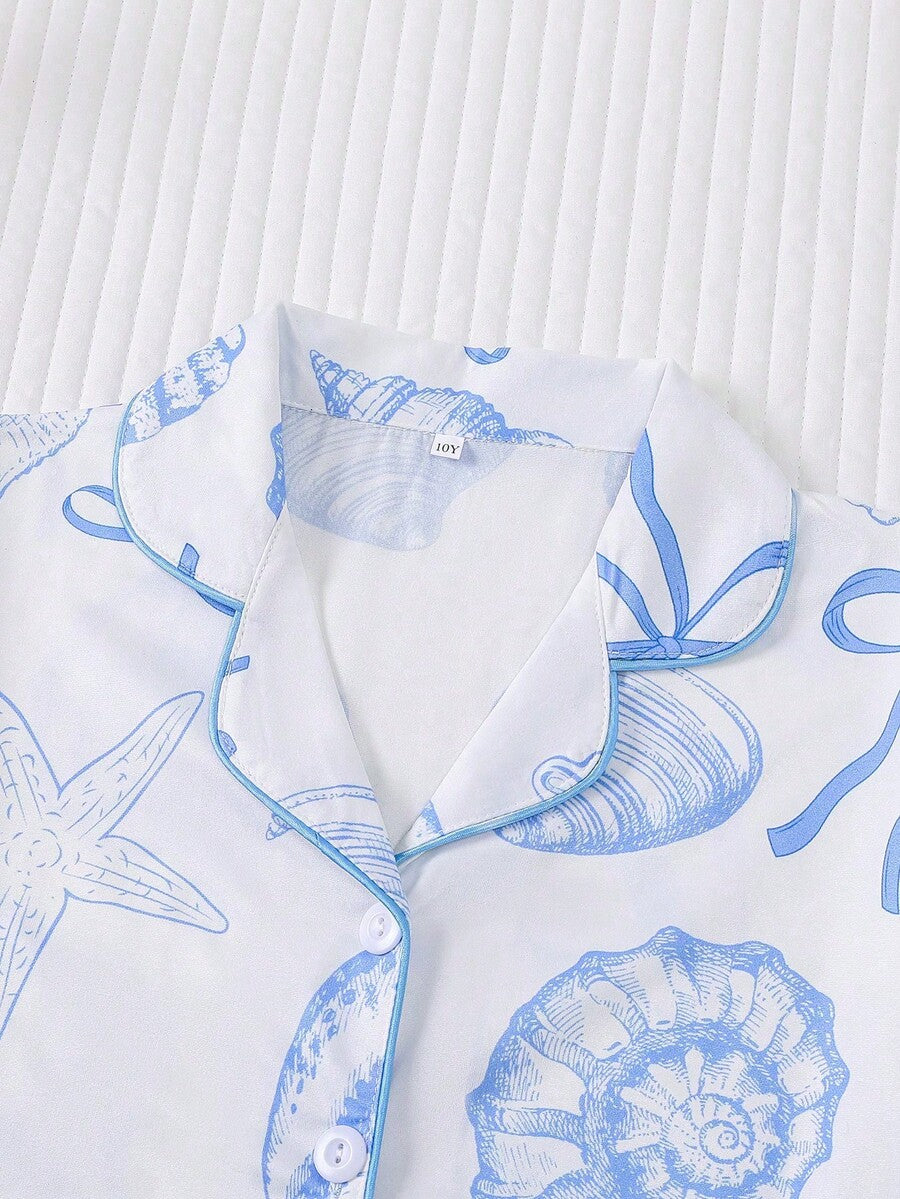 White 2-piece tween girl summer pajama set with blue ocean and seashell print featuring a short sleeve lapel cardigan top and matching elastic waist shorts.