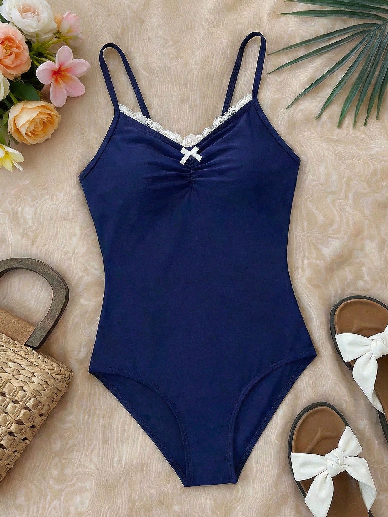 Tween girls' one-piece swimsuit featuring a ruffle splice front, ruched detailing, bow accent, contrast lace trim, and spaghetti straps.