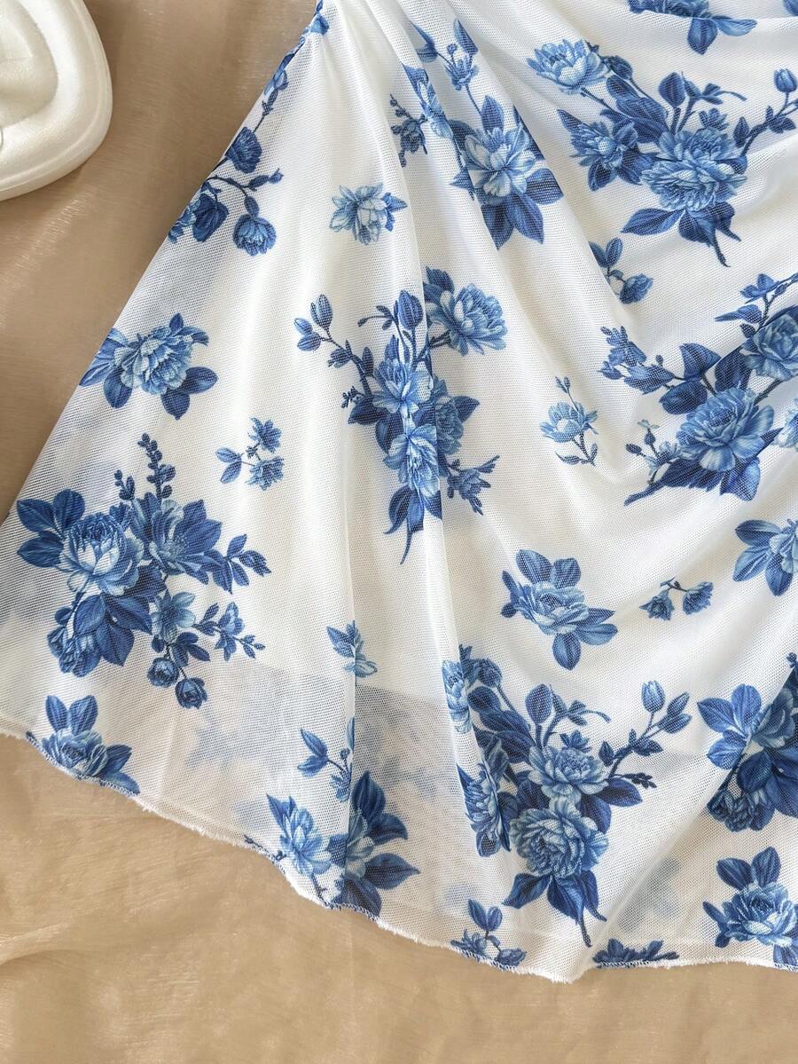 Tween girl yellow mini sundress with large pink floral hibiscus print, spaghetti straps, high waist, flared hem, and sleeveless cami style for summer beach wear