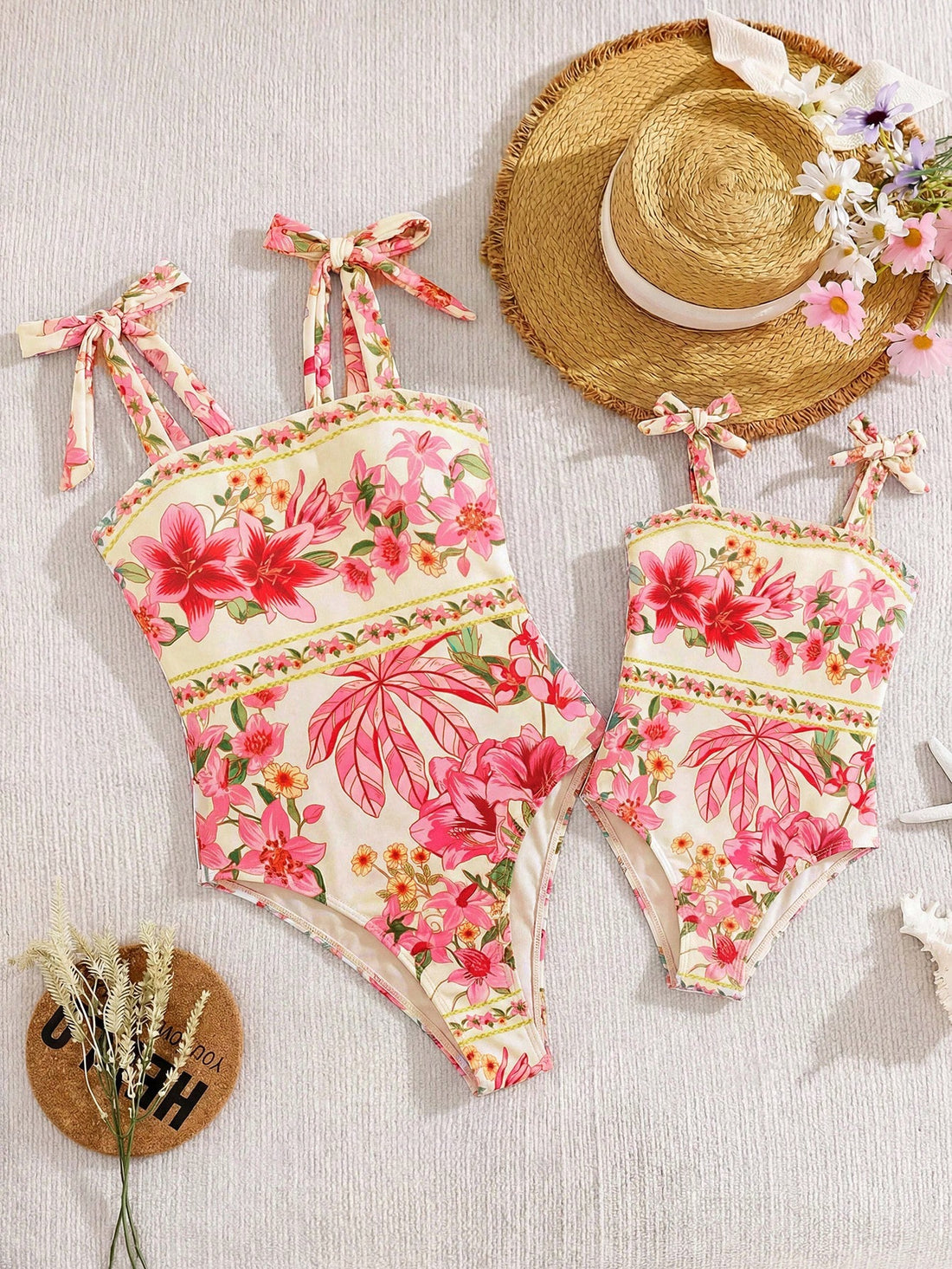 Tween girl floral print one-piece swimsuit with twist front, spaghetti straps, fitted shape, and multicolor all-over hibiscus-inspired pattern for beach and pool wear.